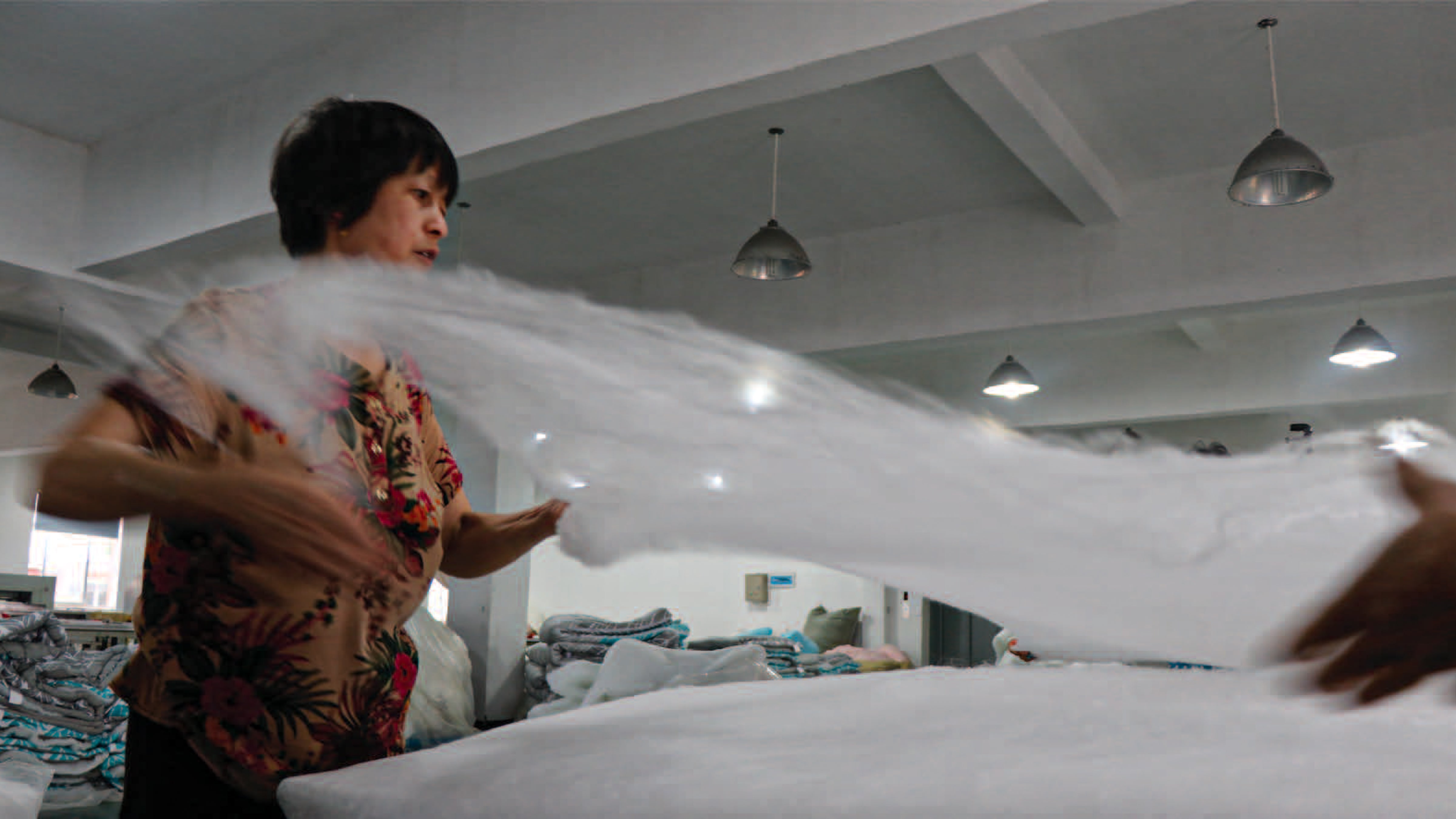 A KAILU artisans hand stretches a piece of fluffy raw silk into a thin sheet, then stacks them to create a luxurious silk-filled Heritage Duvet